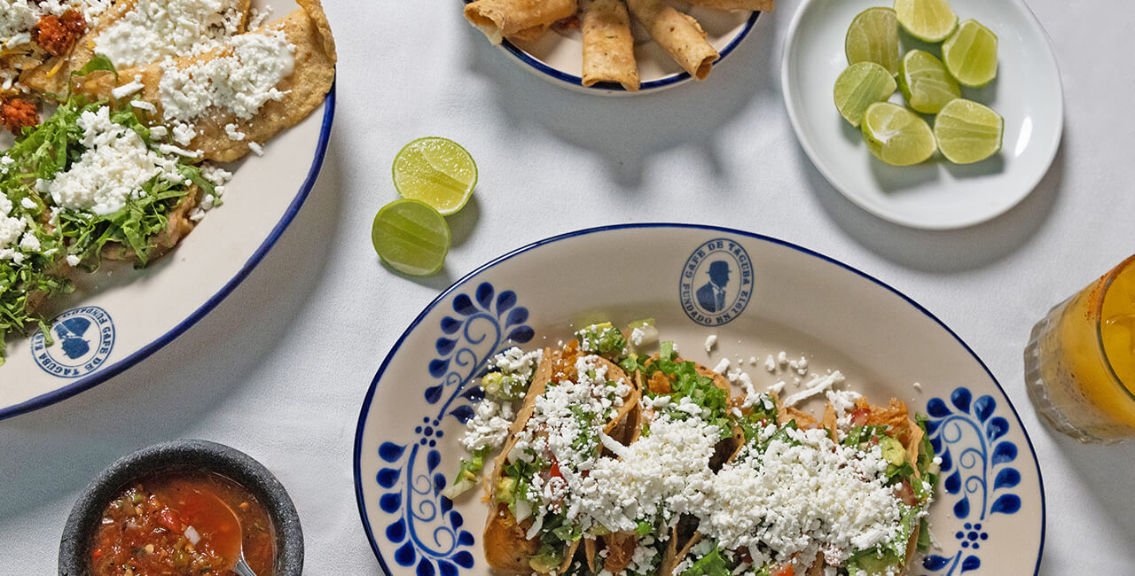 Toma cenital de antojitos mexicanos como quesadillas fritas, empanadas y taquitos dorados, con salsas y limones en el Caf&eacute; de Tacuba.
